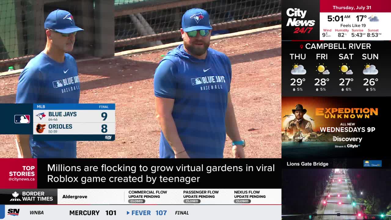 Two men in Blue Jays gear stand on a baseball field, the game's final score displayed on the screen. CityNews Vancouver's weather report and other headlines fill the rest of the frame.
