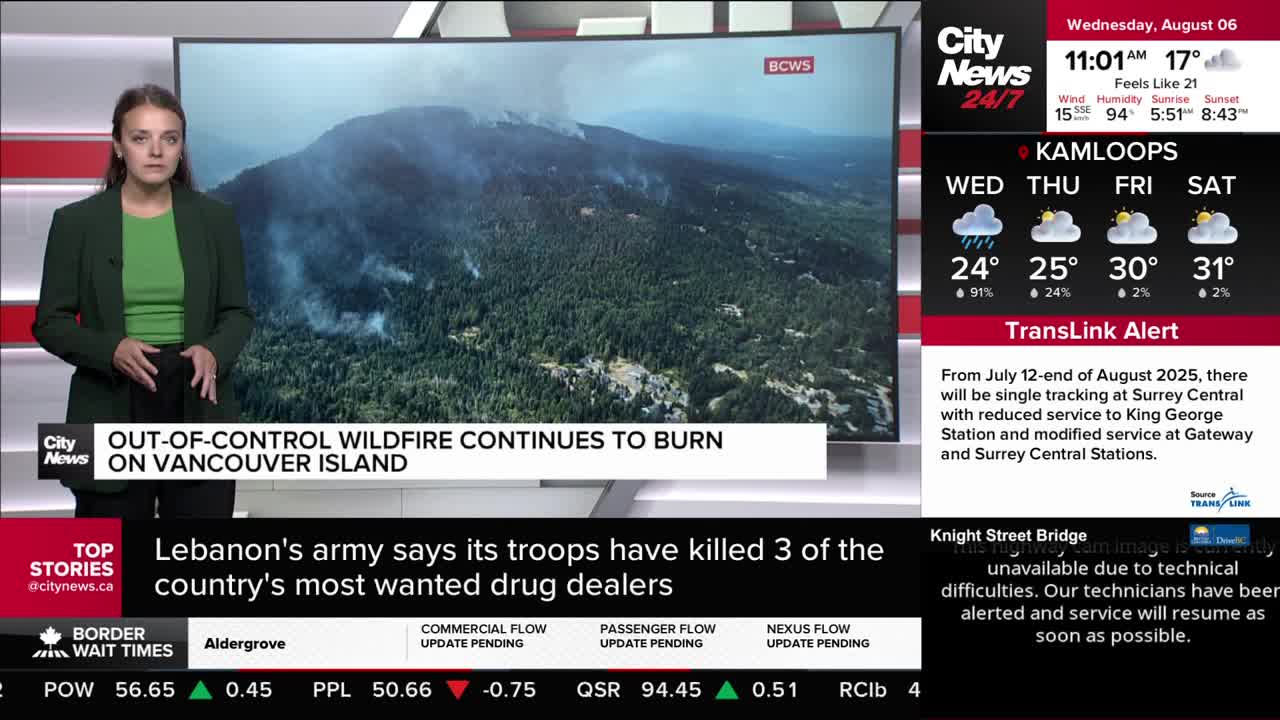 A news anchor from CityNews Vancouver stands in front of a screen showing a wildfire on Vancouver Island. Smoke plumes rise from the dense forest, visible in the background.

