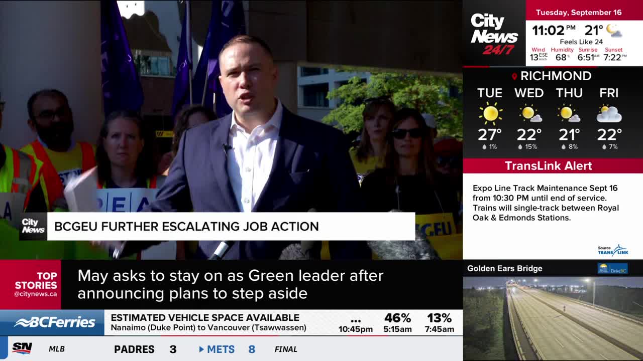 A man in a suit speaks into a microphone, surrounded by a crowd holding signs and purple flags. The CityNews Vancouver graphic at the top of the screen highlights a BCGEU job action.
