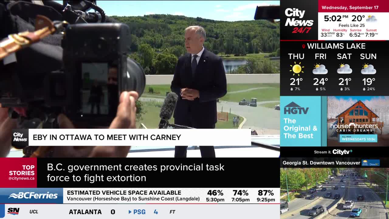 A man in a dark suit stands at a podium, speaking into microphones. A camera crew from CityNews Vancouver is focused on him, capturing the scene.
