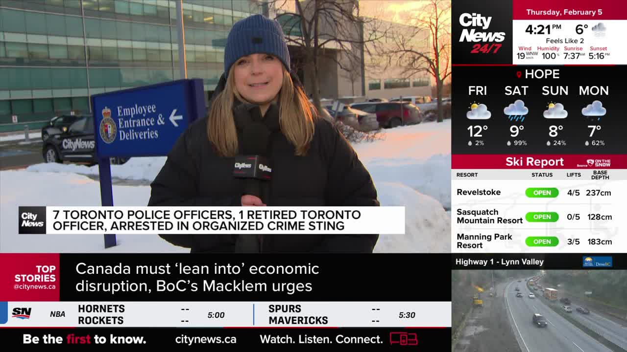 A reporter stands outside a building with a sign for "Employee Entrance & Deliveries," holding a microphone. Cars are parked in a snowy lot behind her, and a CityNews Vancouver graphic displays a news headline about arrests.