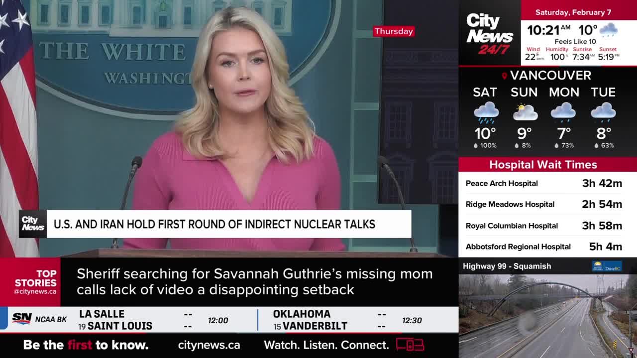 A woman in a pink sweater speaks at a podium, the U.S. flag behind her. City News Vancouver's broadcast shows a forecast for rain in the city and hospital wait times.