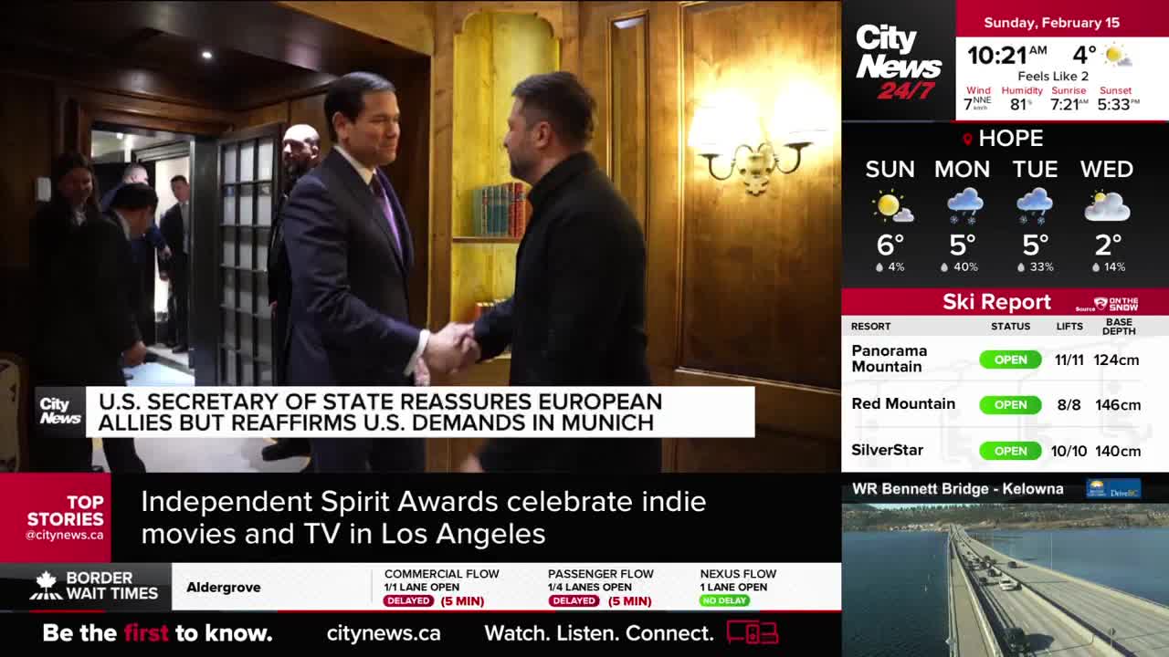 Two men shake hands in a hallway, one in a dark suit and the other in a black jacket. Behind them, other men in suits are visible. Two men shake hands in a hallway, one in a dark suit and the other in a black jacket. Behind them, other men in suits are visible.