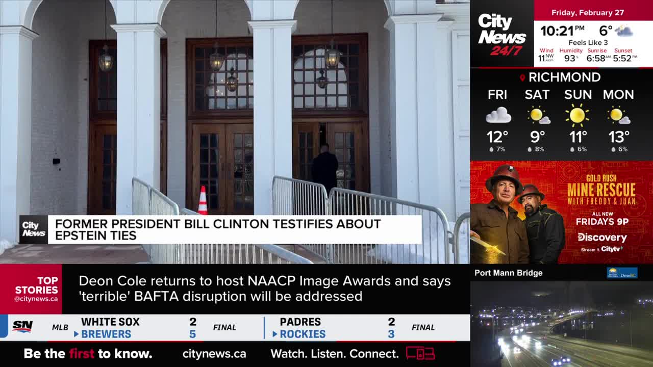 A man in a dark coat walks through the large wooden doors of a building. A white barricade guides people up a ramp towards the entrance. A man in a dark coat walks through the large wooden doors of a building. A white barricade guides people up a ramp towards the entrance.