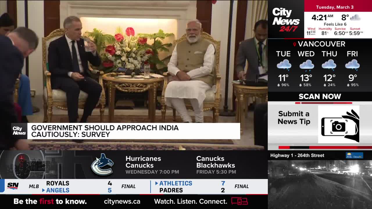 Two men in suits sit in ornate chairs, one drinking from a glass. The other man, in traditional Indian attire, sits with his hands folded.