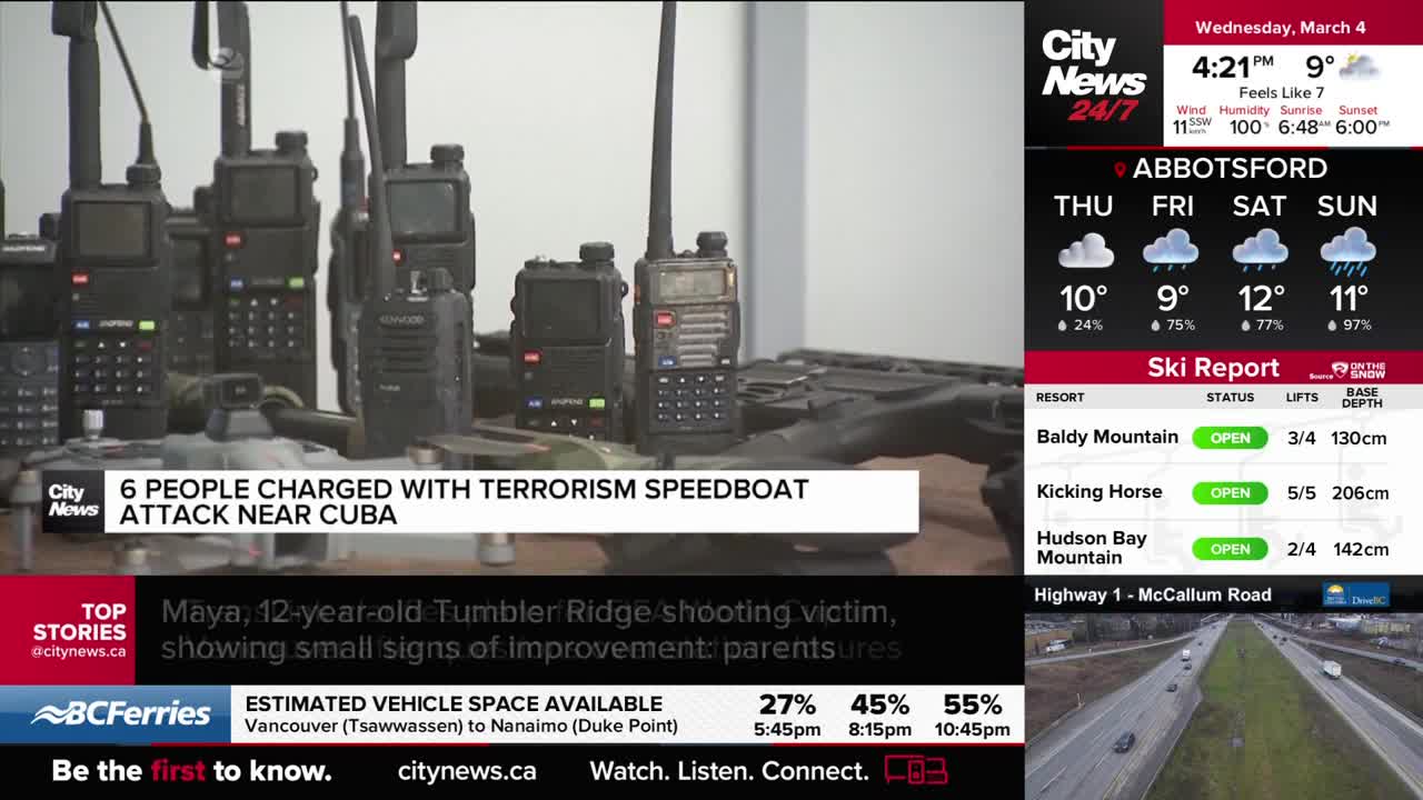 A row of black walkie-talkies sits on a table, some with antennas extended. A news ticker at the bottom of the screen reports on a shooting victim in Tumbler Ridge.