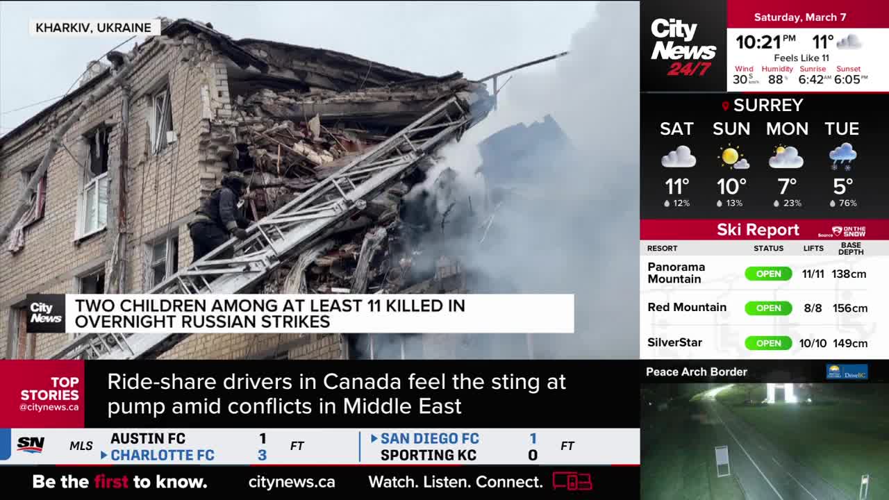 Firefighters climb a ladder against a damaged, smoke-filled building. The CityNews Vancouver screen displays a ski report for Panorama Mountain, Red Mountain, and SilverStar, all open.