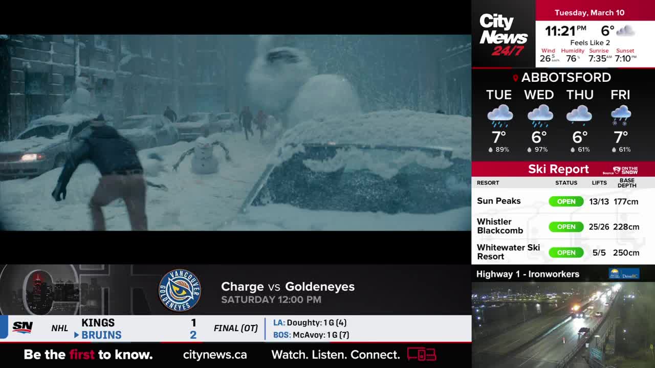 A figure in a dark jacket runs through heavy snow, past abandoned, snow-covered cars. A snowman stands eerily in the middle of the street.