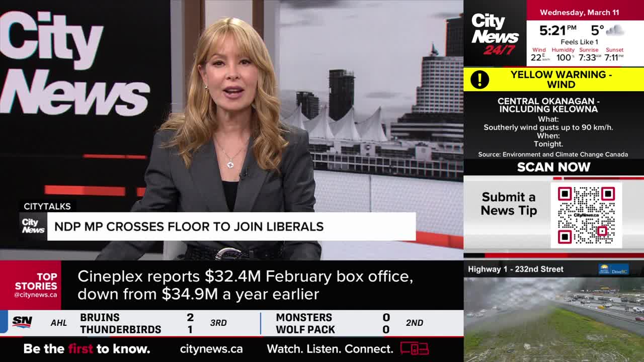 A woman with blonde hair, wearing a grey blazer, speaks from a news studio. A graphic behind her announces an NDP MP crossing the floor to join the Liberals.