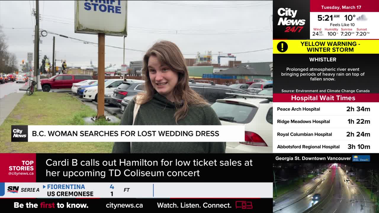 A woman stands outside a thrift store, talking to the camera. Cars are parked in a lot behind her, and traffic moves along a street in the distance.