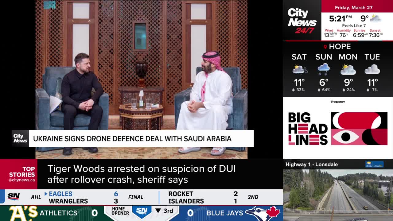 The screen shows a news report about Ukraine signing a drone defence deal with Saudi Arabia. Below that, a headline announces Tiger Woods' arrest on suspicion of DUI.