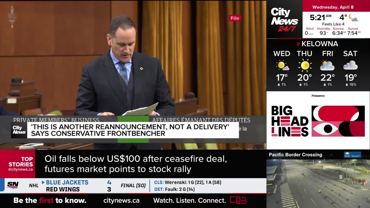 A man in a suit stands at a podium, reading from papers. On the screen, a headline declares, "'This is another reannouncement, not a delivery,' says Conservative frontbencher."