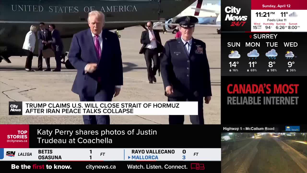 A man in a dark suit and a pink tie walks forward, his mouth open as if speaking. Beside him, a person in a military uniform strides with purpose. Behind them, a large helicopter, marked "UNITED STATES OF AMERICA," sits on the tarmac.