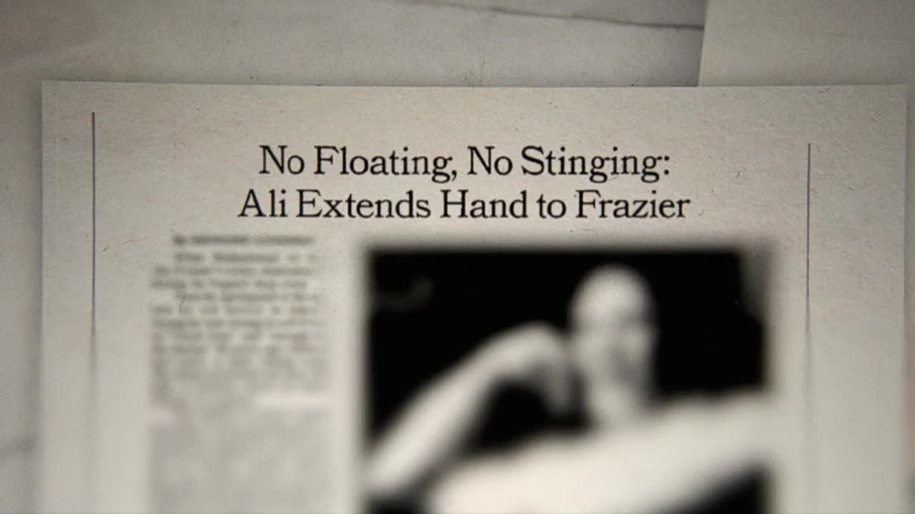 A newspaper headline, "No Floating, No Stinging: Ali Extends Hand to Frazier," sits in the foreground. A blurry image of the boxers is visible below the text.
