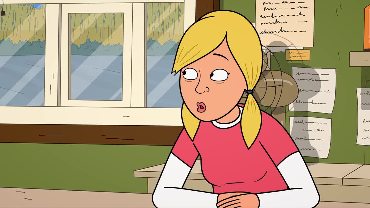 A blonde woman with pigtails stares off to the side, her mouth slightly open in surprise. Behind her, a fan spins, and papers are tacked to the wall.
