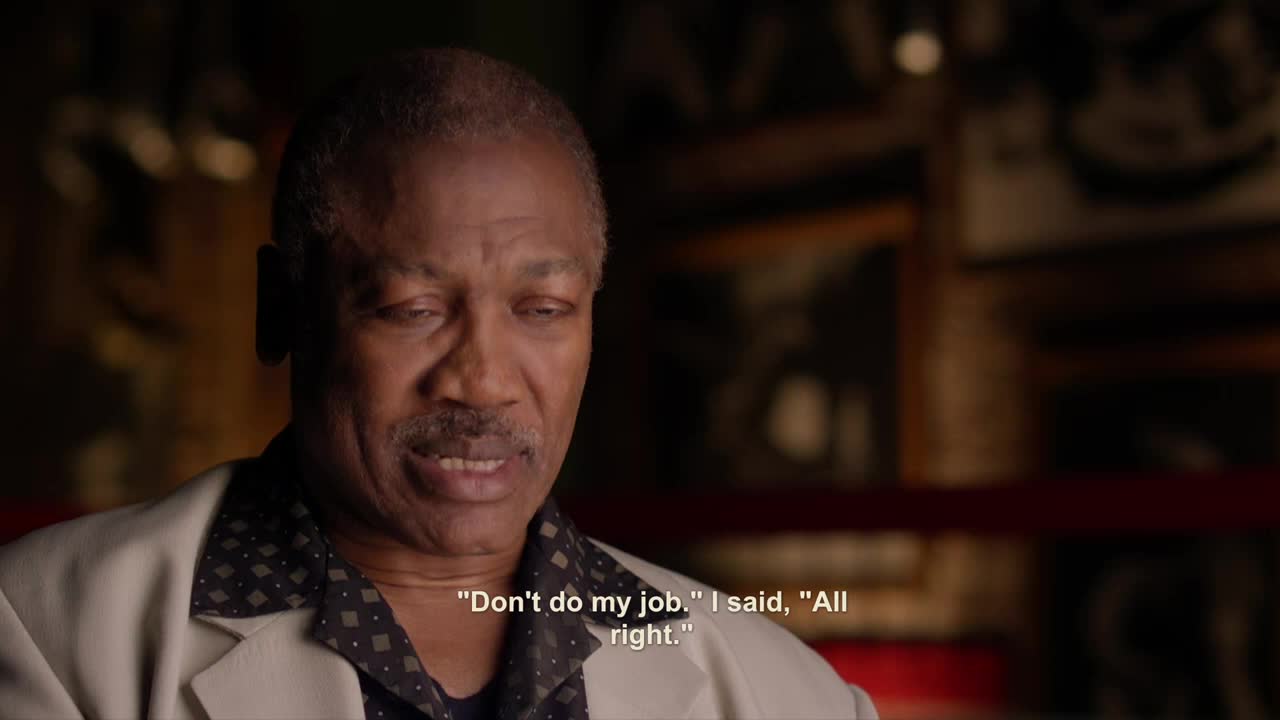 The man in the cream-colored jacket is speaking, his expression thoughtful. Below him, text from Crave 2 quotes his words: "Don't do my job. I said, 'All right.'"
