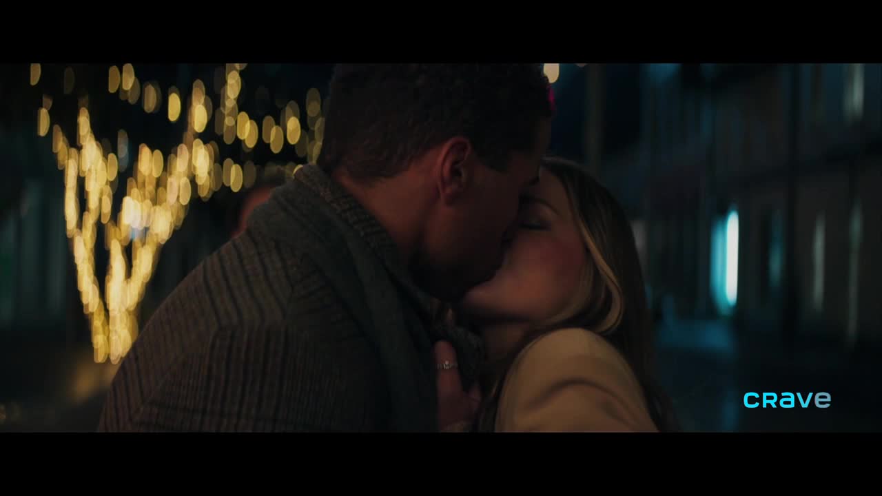 A couple is locked in a kiss, their faces close, illuminated by the soft glow of string lights. The Crave logo is visible in the corner, hinting at a romantic scene from a Canadian production.
