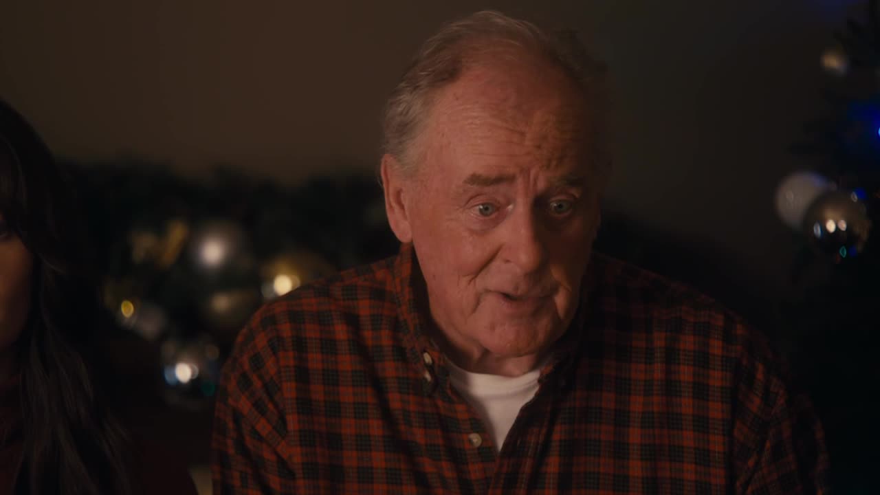 The older man in the plaid shirt is speaking, his expression a mix of concern and surprise. Behind him, a Christmas tree glows softly, suggesting a holiday gathering on Crave 4.
