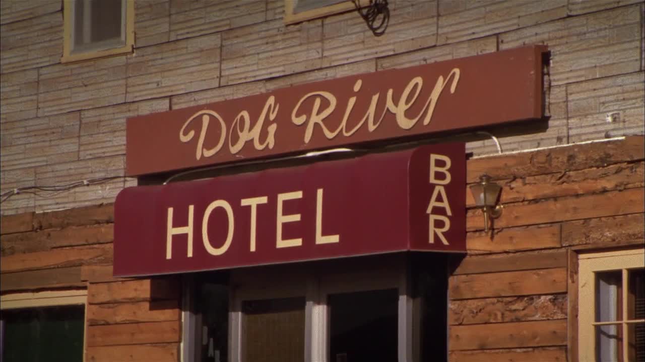 The "Dog River Hotel" sign, with its elegant script, hangs above the entrance. Below, the maroon awning of the hotel's bar is visible, a familiar sight from the Canadian comedy series on Crave 4.

