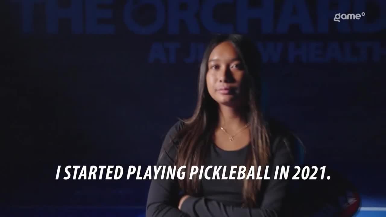 A woman with long, dark hair stands in front of a dark background, looking directly at the camera. The text "I STARTED PLAYING PICKLEBALL IN 2021" is displayed below her.
