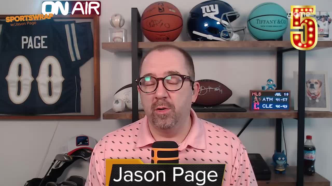 Jason Page, from Game+ in Canada, is speaking into a microphone, his name displayed in a lower third. Behind him, shelves hold sports memorabilia and a small scoreboard displays MLB scores.
