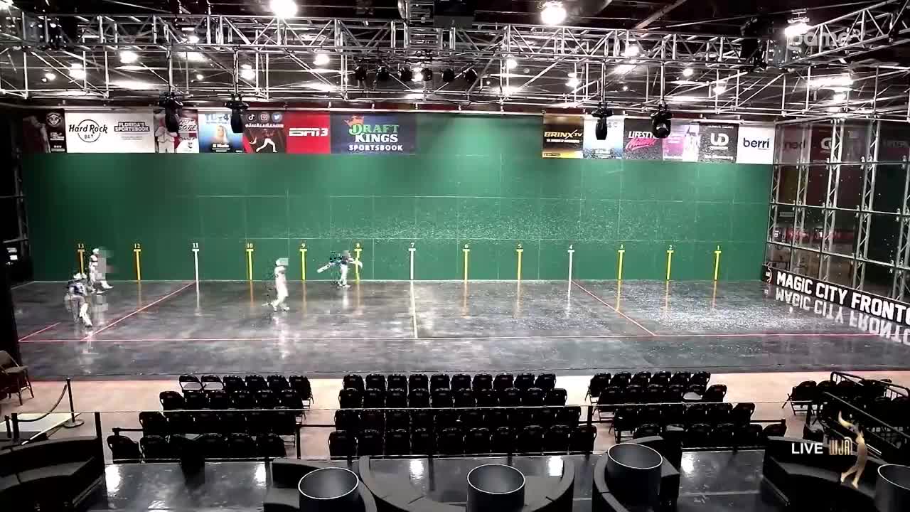 Players in white uniforms are moving quickly, striking a small ball against the green wall. The game is underway, with the action taking place in a large indoor court, likely in Canada, as it's being broadcast on Game+.
