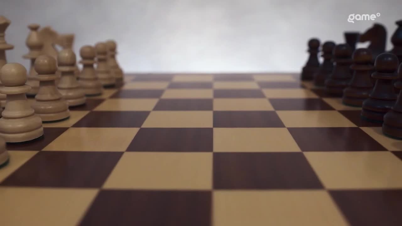 The chess pieces, light and dark, stand in formation on the checkered board, ready to begin. The camera angle is low, giving a sense of anticipation for the game.
