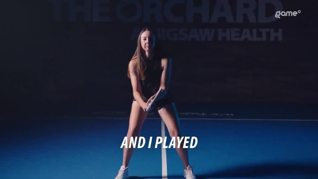 A woman stands centered on a tennis court, holding a racket in front of her. The words "AND I PLAYED" are written across the bottom of the screen.
