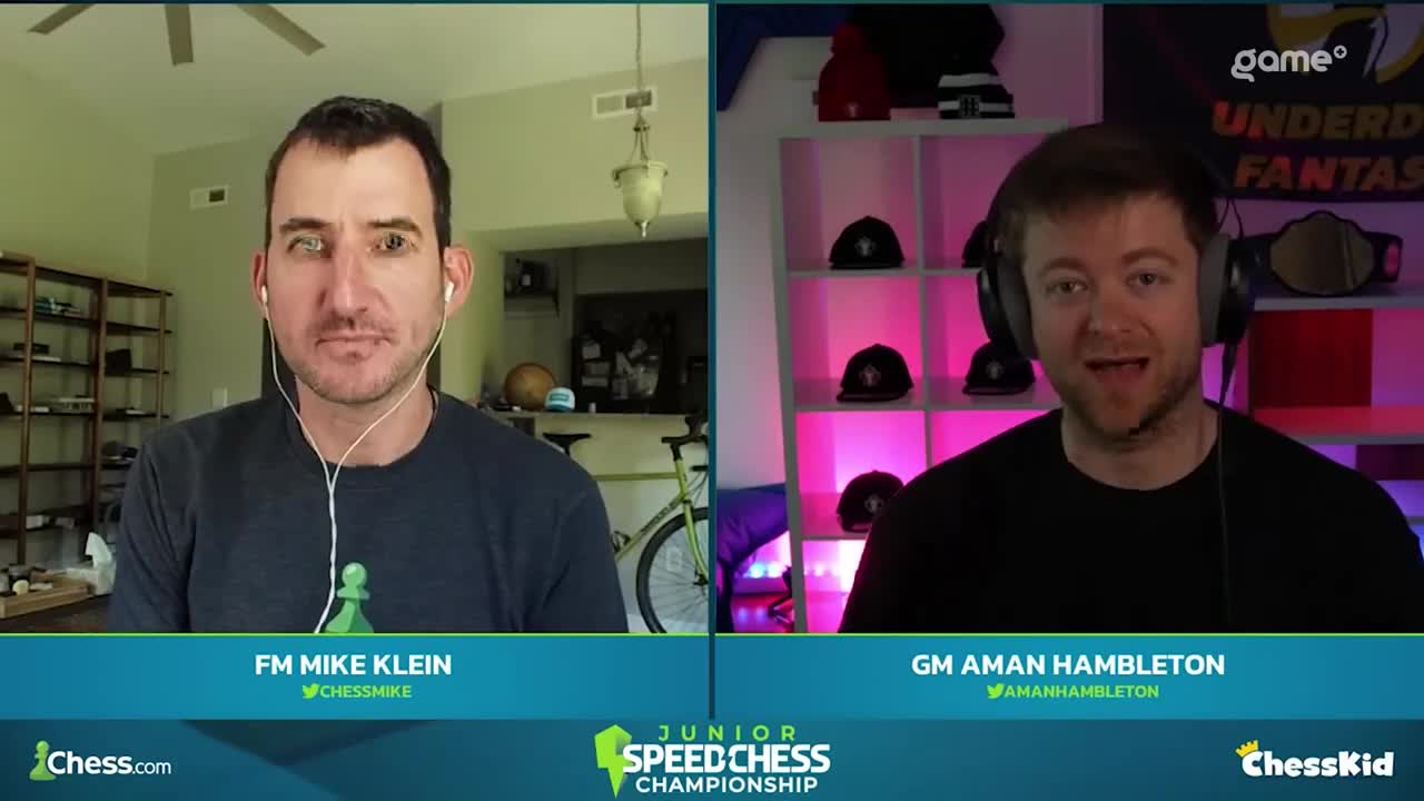 Mike Klein, with a green chess piece on his desk, is listening intently while Aman Hambleton, wearing a headset, speaks animatedly from what appears to be a Game+ studio in Canada. The Junior Speed Chess Championship is underway.

