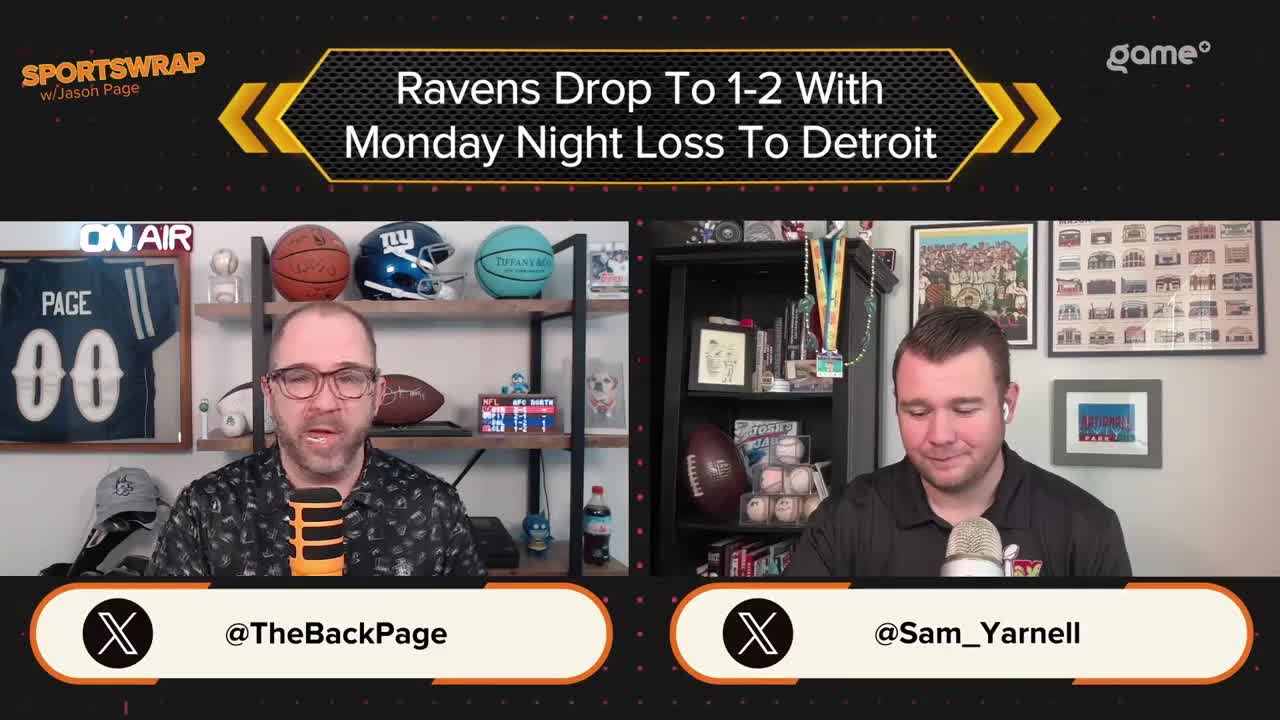 Two men sit at a desk, each with a microphone, discussing the Ravens' loss. The Game+ logo is visible, and behind them, shelves display sports memorabilia.
