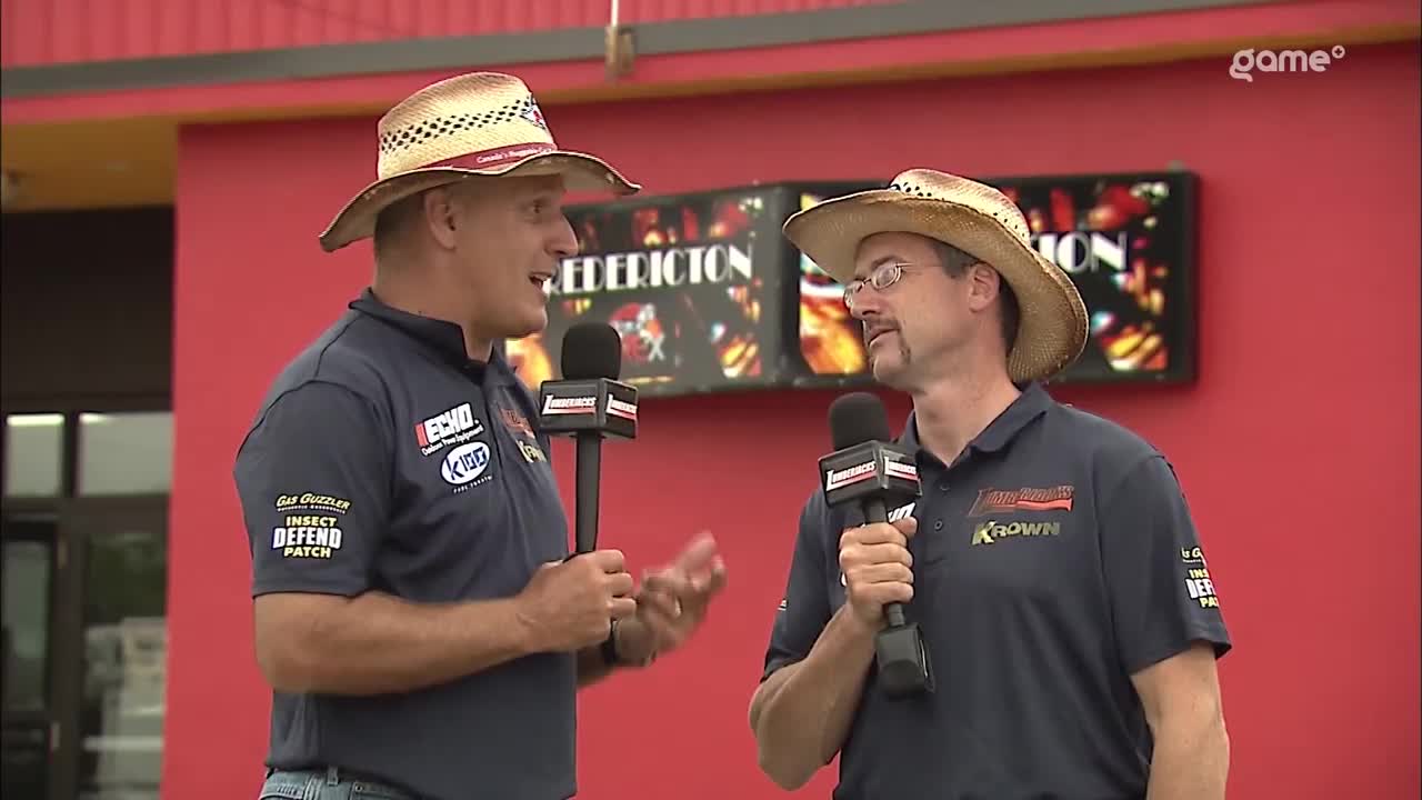 Two men in cowboy hats are holding microphones and talking to each other, with a "Fredericton" sign visible behind them. They're on the Game+ broadcast, likely reporting on a Canada event.
