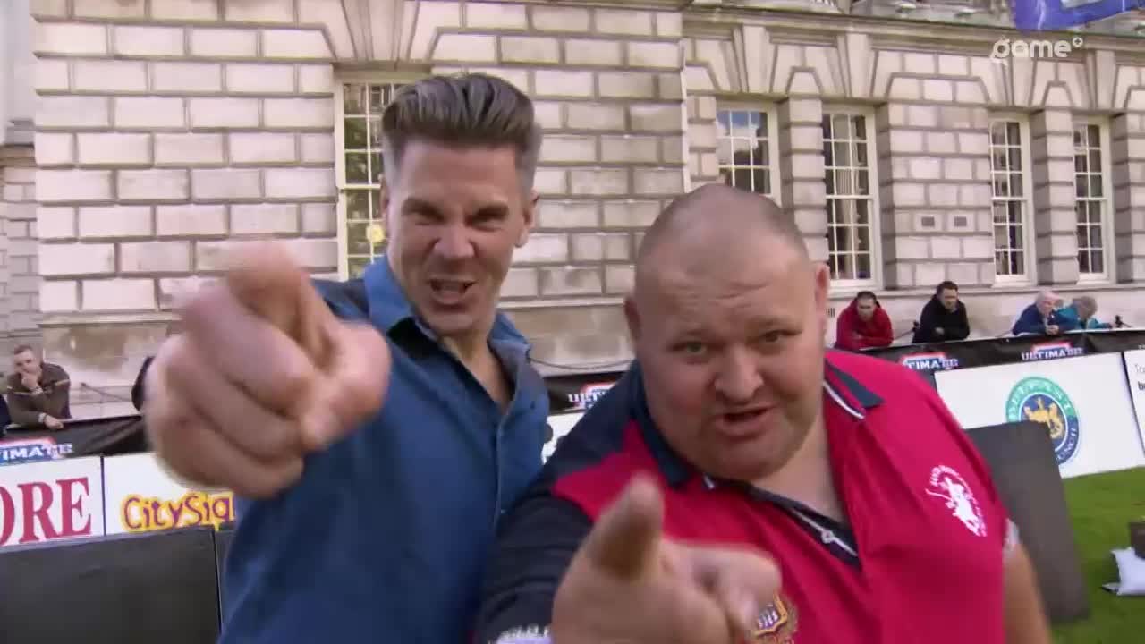 Two men are pointing directly at me, their faces animated and speaking. Behind them, a building with large windows stands against a bright sky. Two men are pointing directly at me, their faces animated and speaking. Behind them, a building with large windows stands against a bright sky.