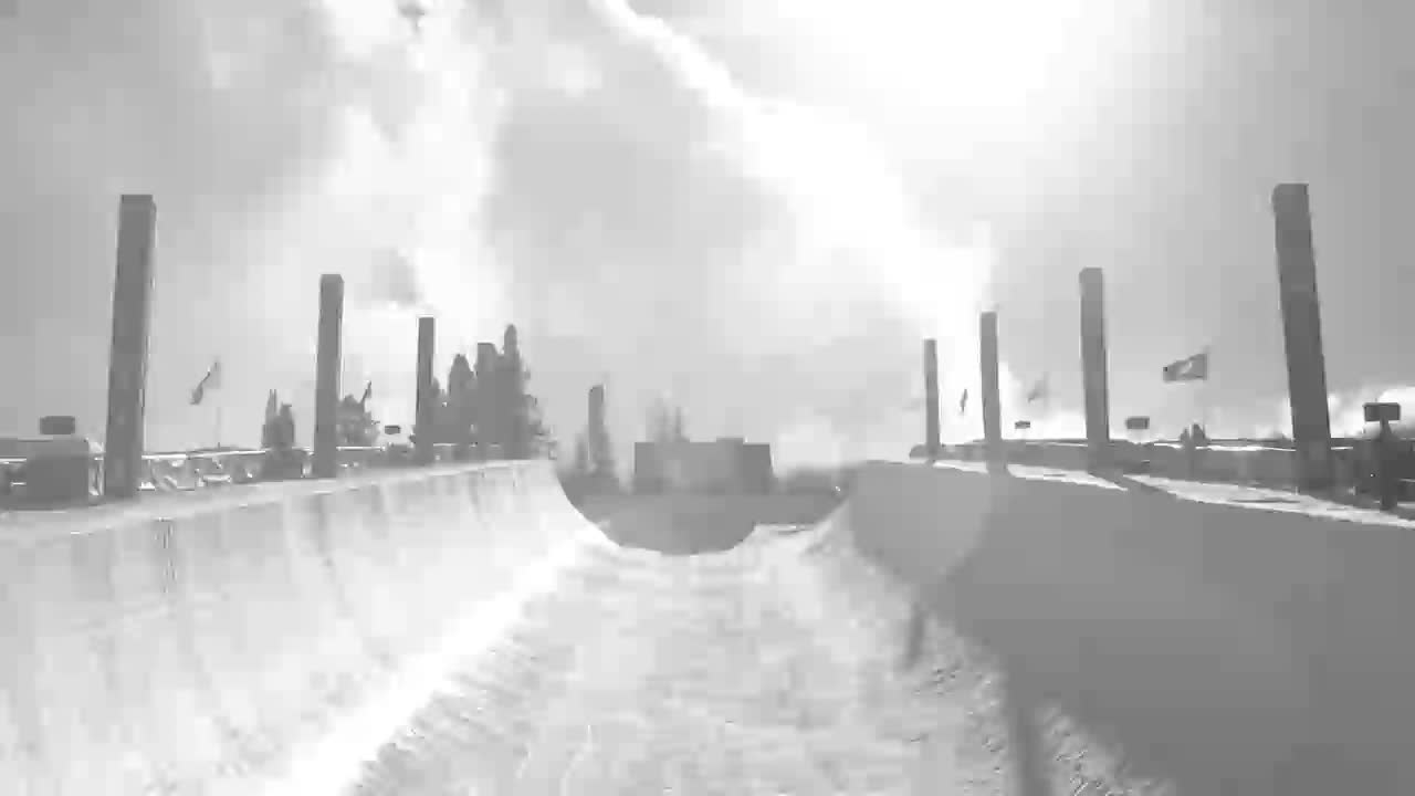 A snowboarder carves down the icy halfpipe, the Canadian flag flapping in the background. The bright sun glints off the snow as they prepare for their next jump.