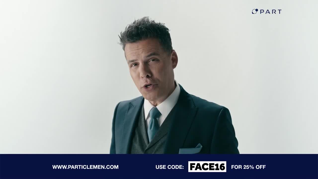 A man in a sharp suit speaks directly to the camera. A dark blue band at the bottom displays a website and a discount code.