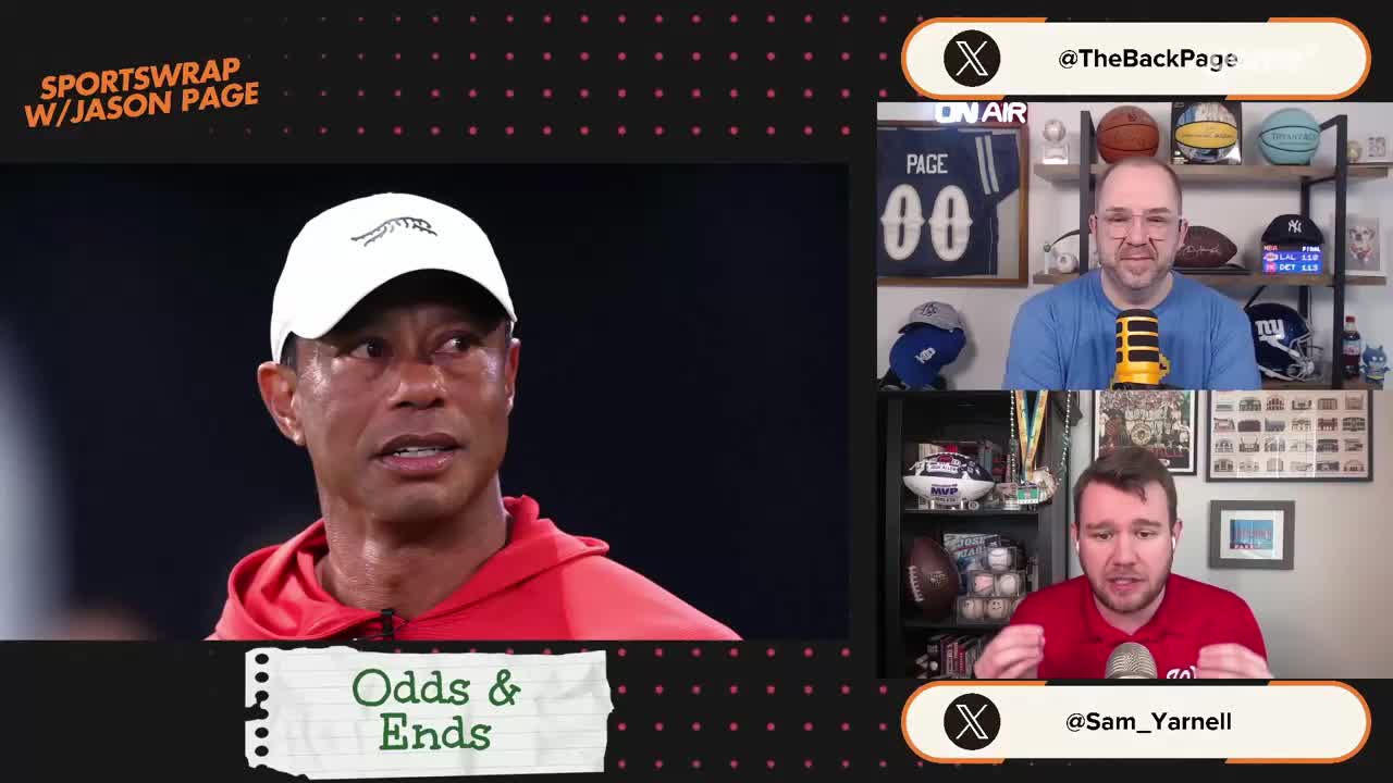 Tiger Woods, wearing a white cap and red hoodie, looks intently off-camera. Two men are on a split screen, one in a blue shirt and the other in a red shirt, both speaking into microphones.