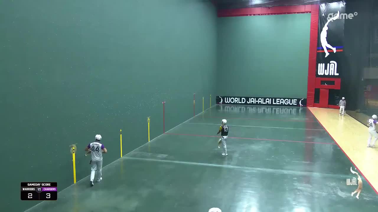 A player in a white jersey with purple trim, number 44, sprints down the court. Another player, wearing number 13, moves towards the wall.