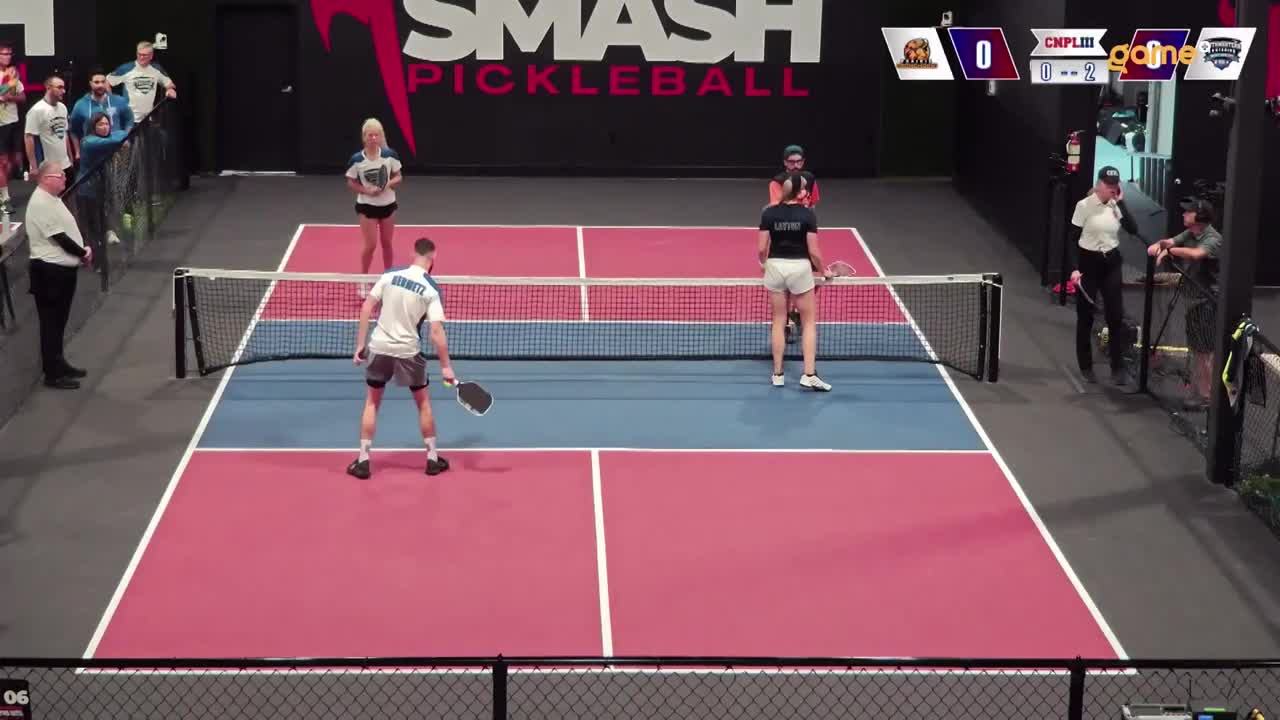 A man in a white shirt and grey shorts stands ready on the court, paddle in hand. Across the net, a woman in a black shirt and white shorts waits for the next shot. The score is tied at 0-0, broadcast on Game+ for viewers in Canada.