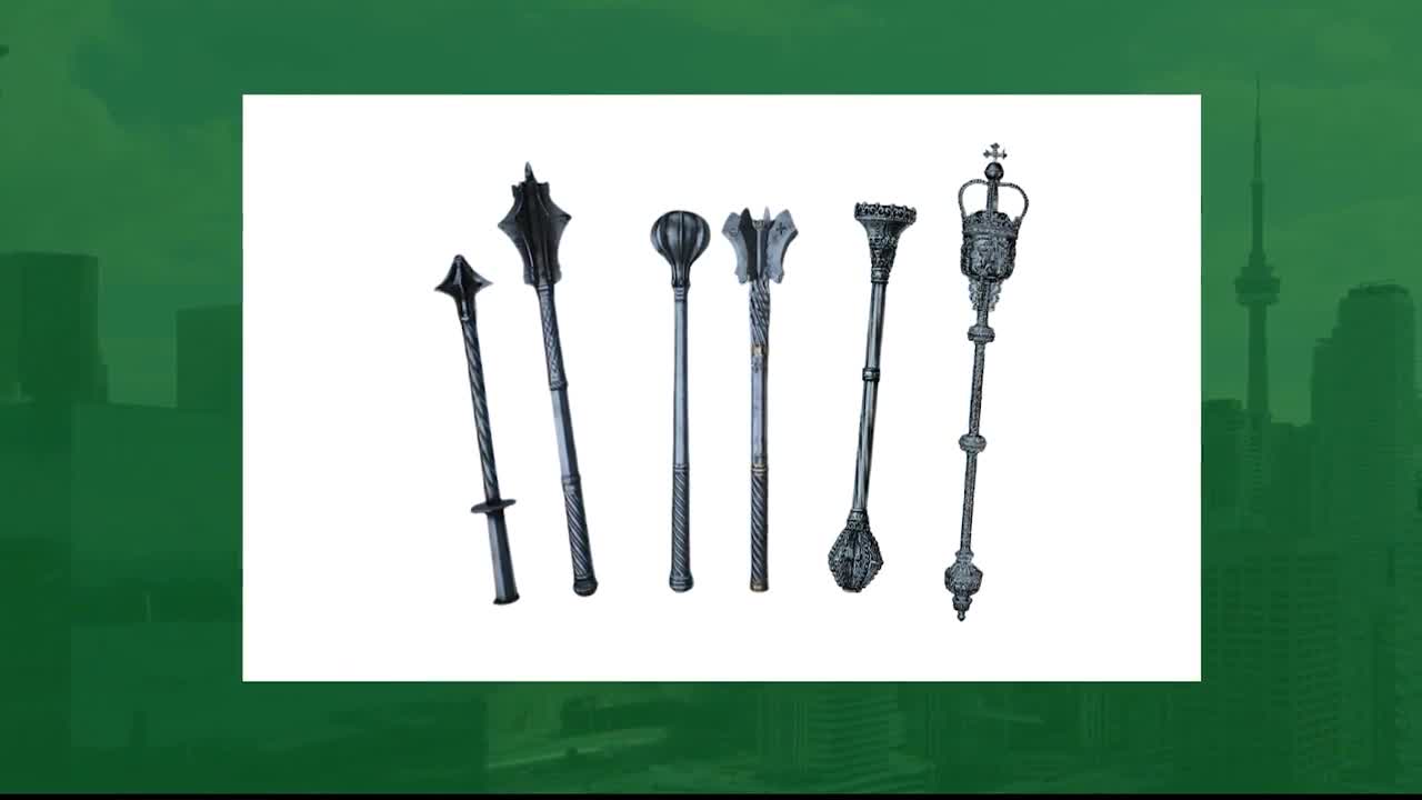 Seven ornate maces, each with a unique head, are lined up against a stark white background. The backdrop of the Legislative Assembly of Ontario, with the CN Tower visible, provides a subtle contrast to the display of these ceremonial objects.
