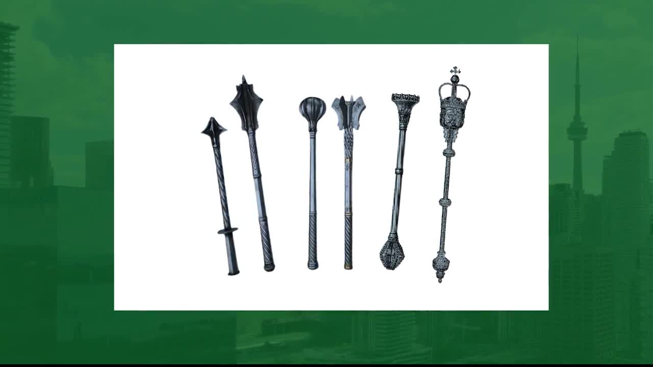 Six ceremonial maces, including the one from the Legislative Assembly of Ontario, are lined up against a white background. The CN Tower and Toronto's skyline are just visible in the background.
