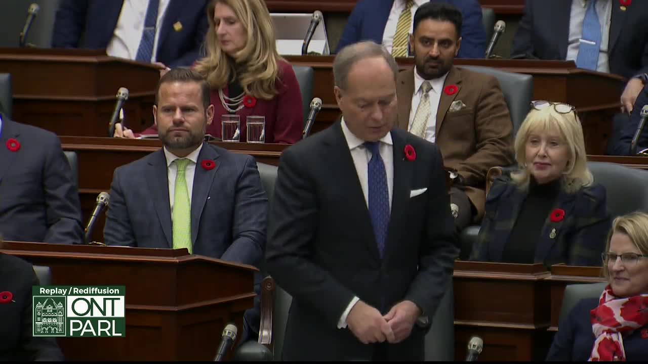 A man in a dark suit, adorned with a poppy, speaks at the Legislative Assembly of Ontario. Other members, also wearing poppies, listen intently from their seats.
A man in a dark suit, adorned with a poppy, speaks at the Legislative Assembly of Ontario. Other members, also wearing poppies, listen intently from their seats.