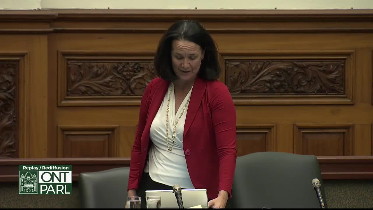 A woman in a red blazer stands at a podium in the Legislative Assembly of Ontario, speaking with a microphone in front of her. The ornate wood paneling behind her suggests the formality of the Canadian government setting.
A woman in a red blazer stands at a podium in the Legislative Assembly of Ontario, speaking with a microphone in front of her. The ornate wood paneling behind her suggests the formality of the Canadian government setting.