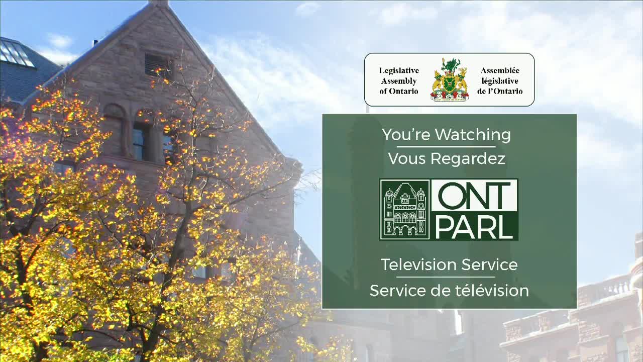 The Legislative Assembly of Ontario's building stands behind a tree with bright yellow leaves. A green screen displays "ONT PARL Television Service."