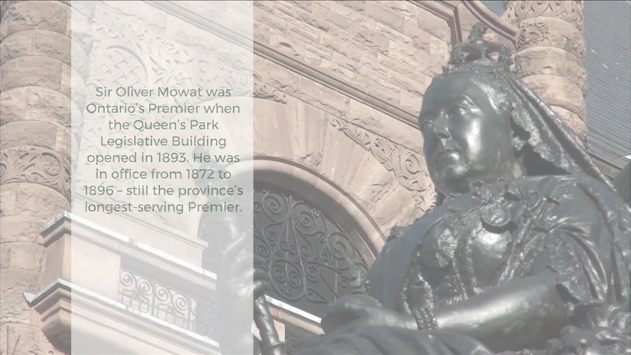 A bronze statue of Queen Victoria stands before the ornate stone facade of the Legislative Assembly of Ontario. The building's intricate carvings and arched windows are visible behind the regal figure.
