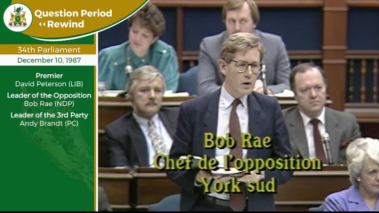 The Leader of the Opposition, Bob Rae, speaks from his seat in the Legislative Assembly of Ontario. Other members of parliament listen intently from the benches.