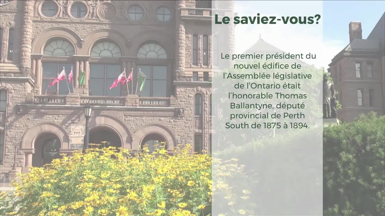 The Legislative Assembly of Ontario building stands tall, its stone facade adorned with flags. A vibrant patch of yellow flowers blooms at its base.