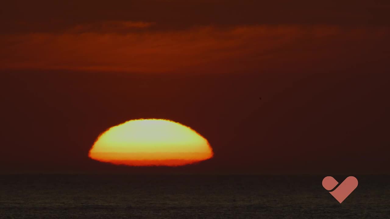 The sun, a fiery orb, dips towards the horizon. Its lower edge touches the dark water, while the sky above deepens into shades of red and orange.
The sun, a fiery orb, dips towards the horizon. Its lower edge touches the dark water, while the sky above deepens into shades of red and orange.