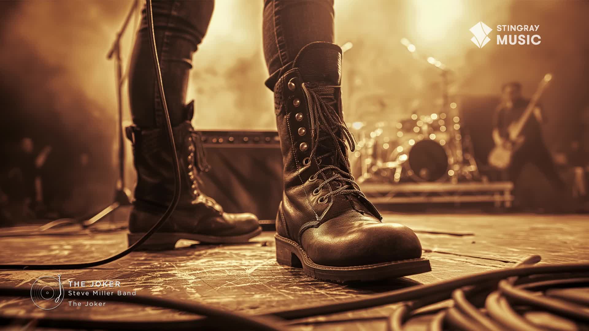 Heavy boots stand firmly on the stage, the leather worn and scuffed. The Steve Miller Band's "The Joker" is about to kick off, and the energy is building.
