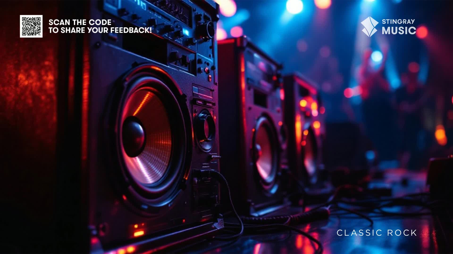 Giant speakers, lit with red and blue, stand ready for a Stingray Classic Rock concert somewhere in Canada. The stage lights are blurred in the background, promising a loud night.
