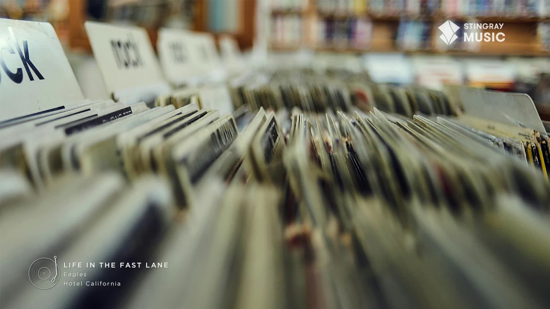 Rows of record albums fill the bins, their spines barely visible behind the "Rock" and "Pop" dividers. The Stingray Music logo sits in the corner, a reminder of the classic sounds playing in the background.
