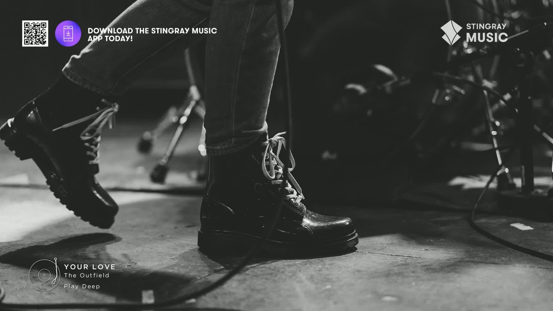 A pair of black boots, laced and scuffed, are the focus as a musician moves across the stage. The Stingray Music logo and "Your Love" by The Outfield suggest a live performance of a classic rock tune in Canada.
